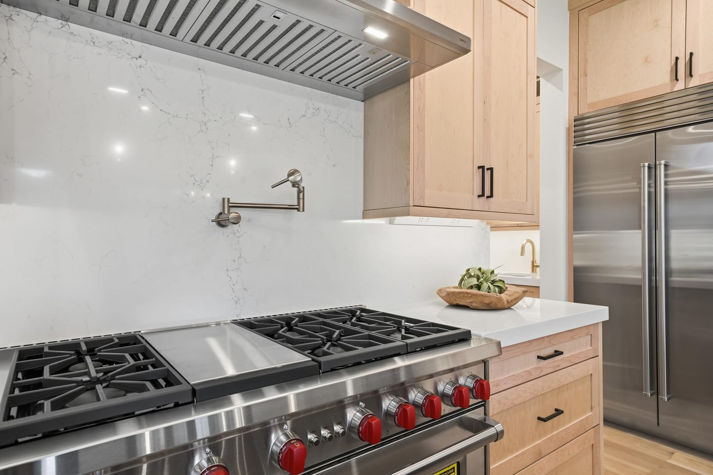 Chef kitchen with white oak cabinetry, quartz island and Wolf range