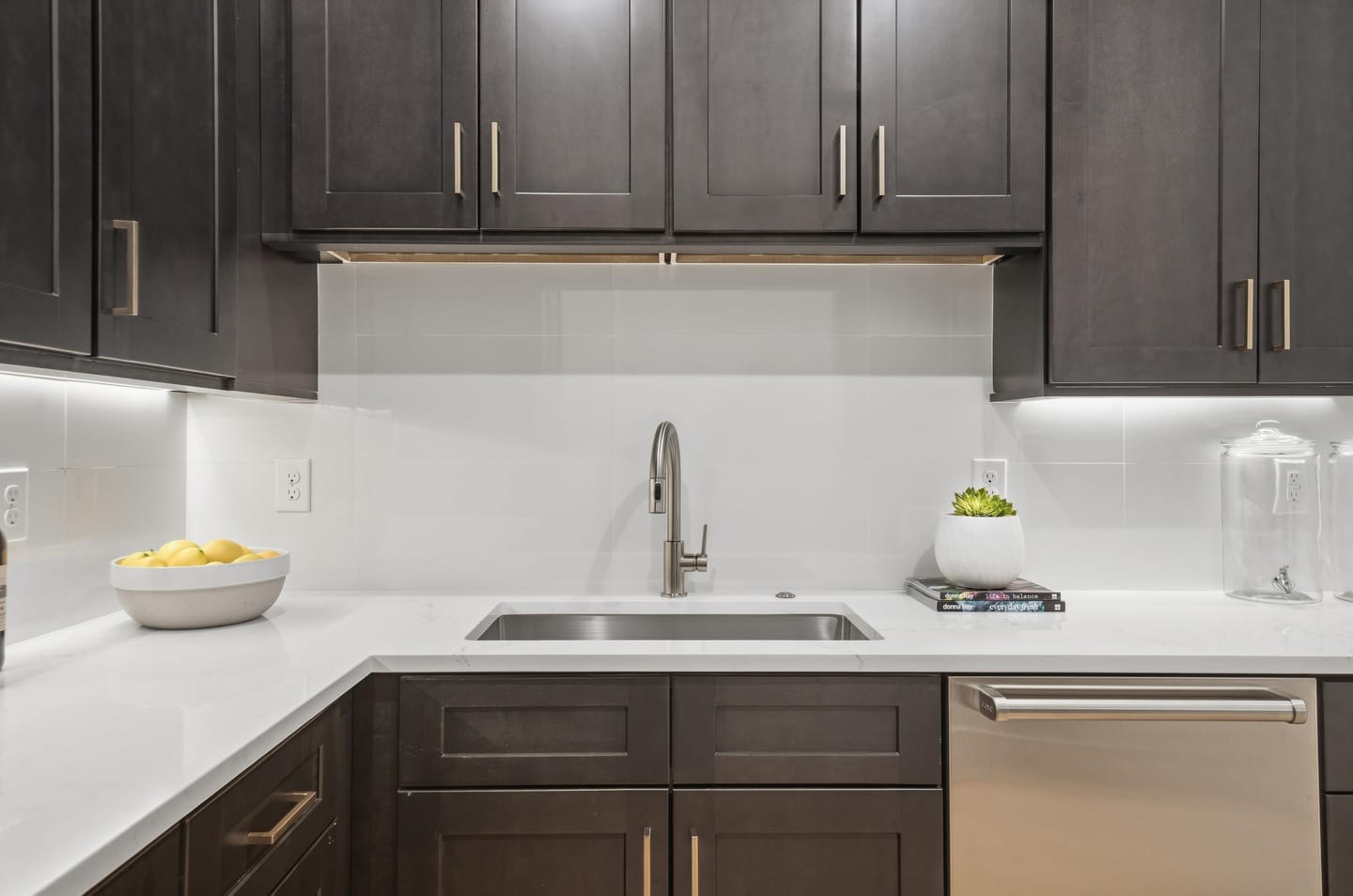 Walk-in pantry with dark cabinetry, sink and quartz counters