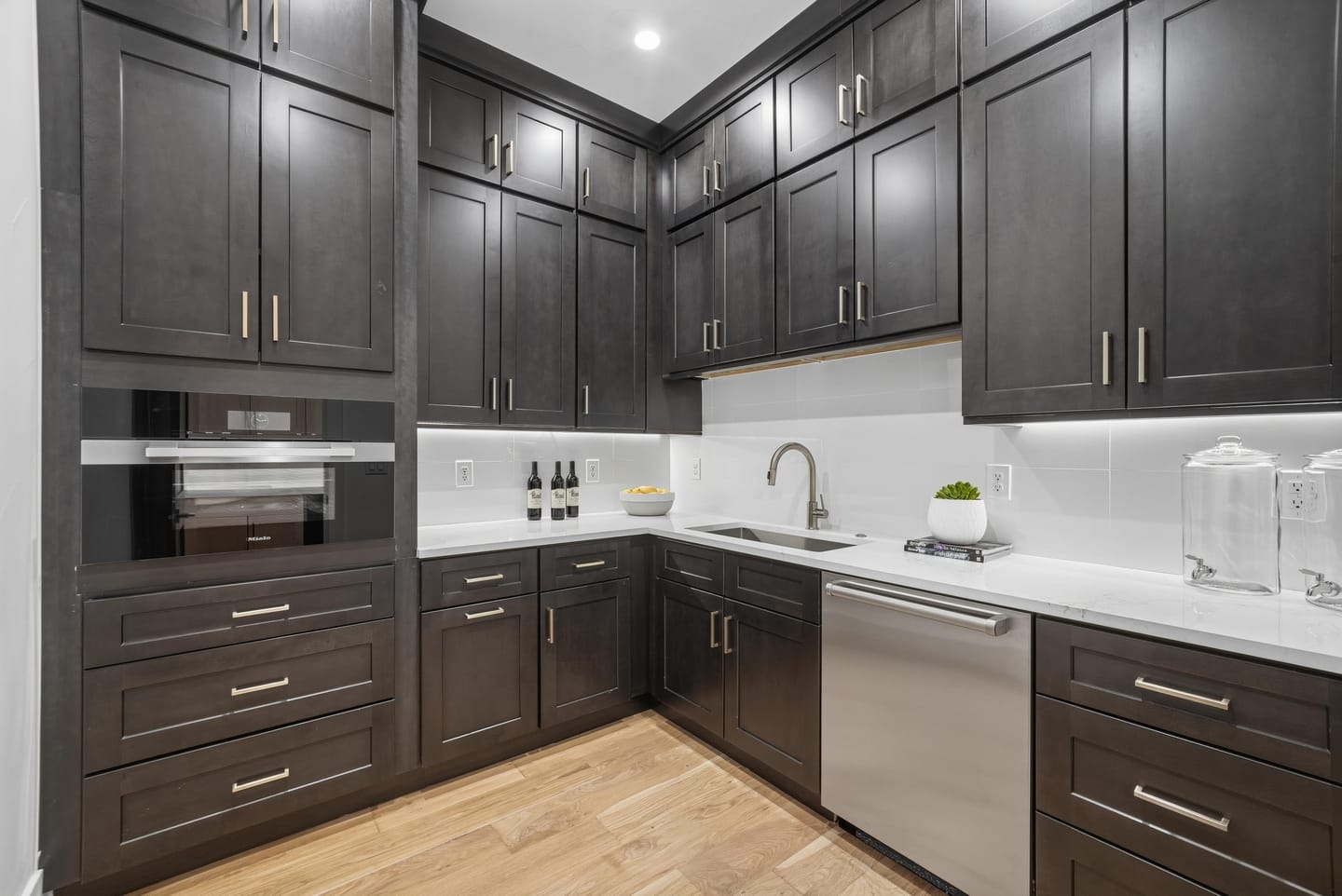 Walk-in pantry with dark cabinetry, sink and quartz counters