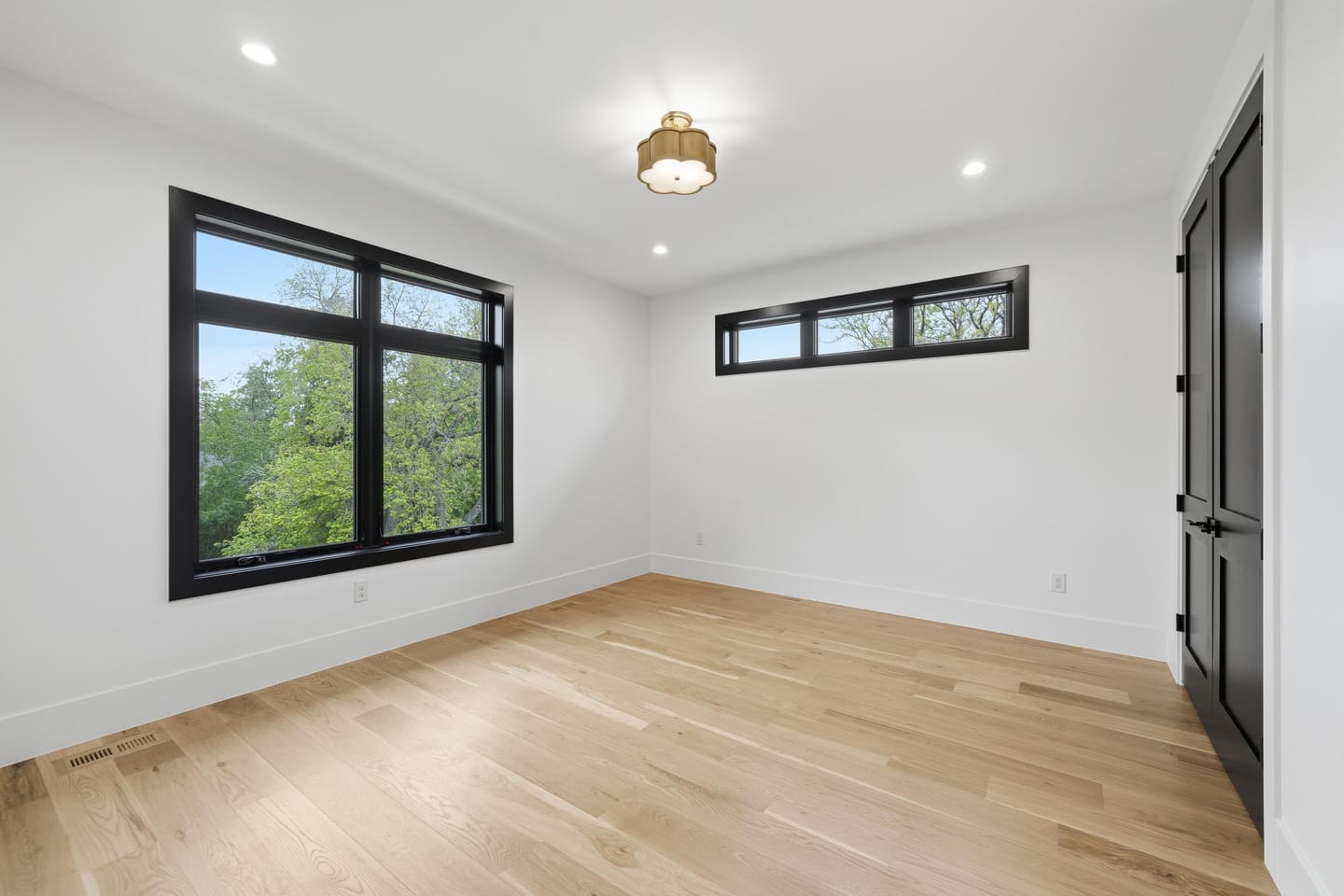 Bedroom with white oak flooring and black-framed windows