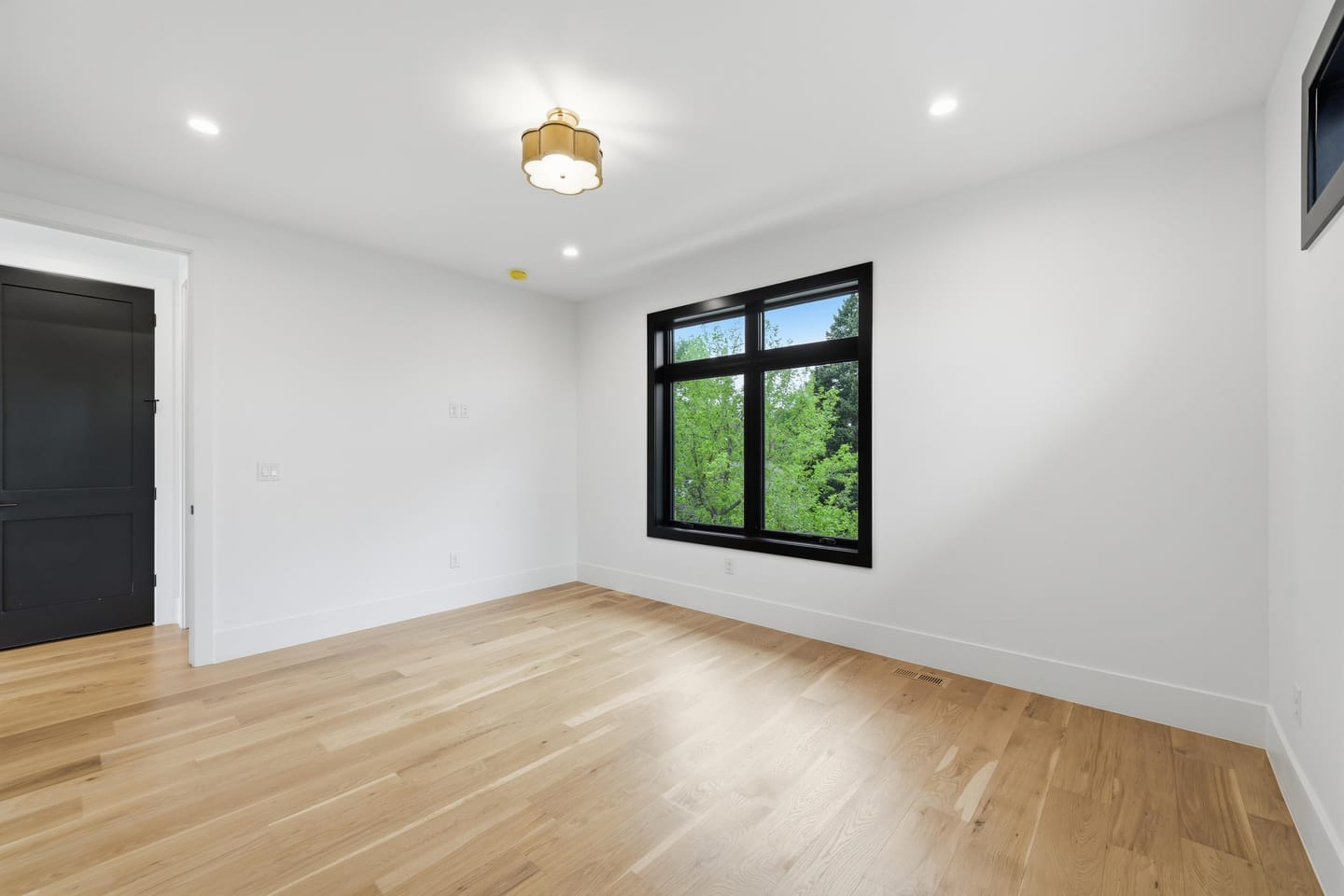 Bedroom with white oak flooring and black-framed windows