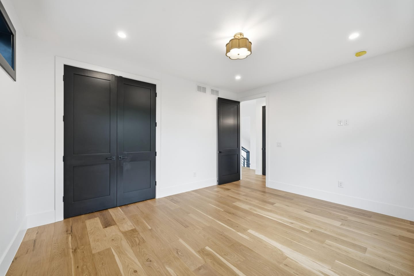 Bedroom with white oak flooring and black-framed windows